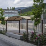 Pérgola exterior de estructura metálica con cubierta textil en una zona ajardinada
