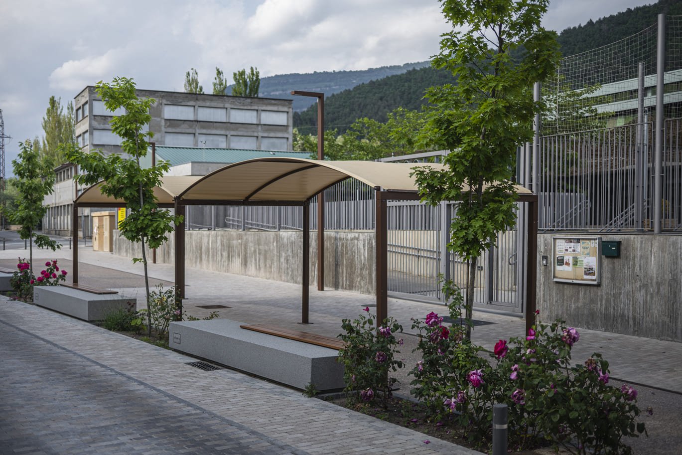 Pèrgola exterior amb estructura metàl·lica Pèrgola exterior d'estructura metàl·lica amb coberta tèxtil a una zona enjardinada